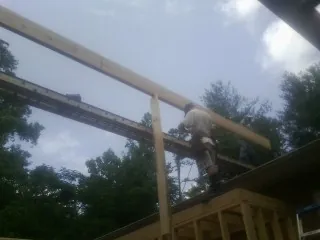 Carpenter setting a ridge beam over a new addition frame — Ice Dam Removal by Roofing Brothers in Albemarle