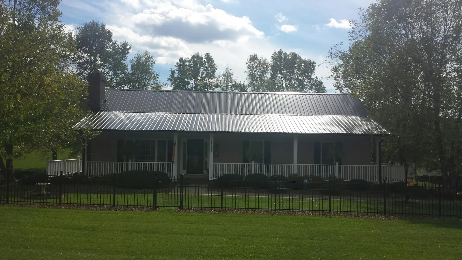 Gray metal roof on a brick ranch with a full width front porch — Gutter Guard Installation work by our crew in Albemarle